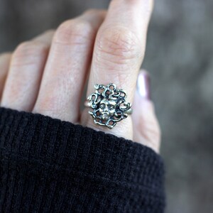Puede incluir: Un anillo de plata con un dise&ntilde;o detallado de la cabeza de Medusa con serpientes como cabello.