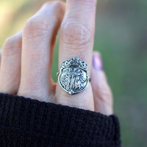 Puede incluir: Un anillo de plata con un dise&ntilde;o detallado de un &aacute;rbol con hojas y ramas. El anillo se lleva en un dedo.