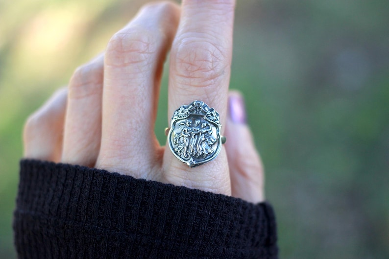 Puede incluir: Un anillo de plata con un dise&ntilde;o detallado de un &aacute;rbol con hojas y ramas. El anillo se lleva en un dedo.