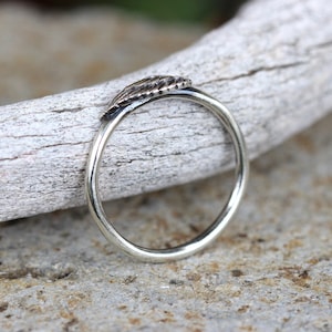 May include: A silver ring with a textured leaf design. The ring is simple and elegant.