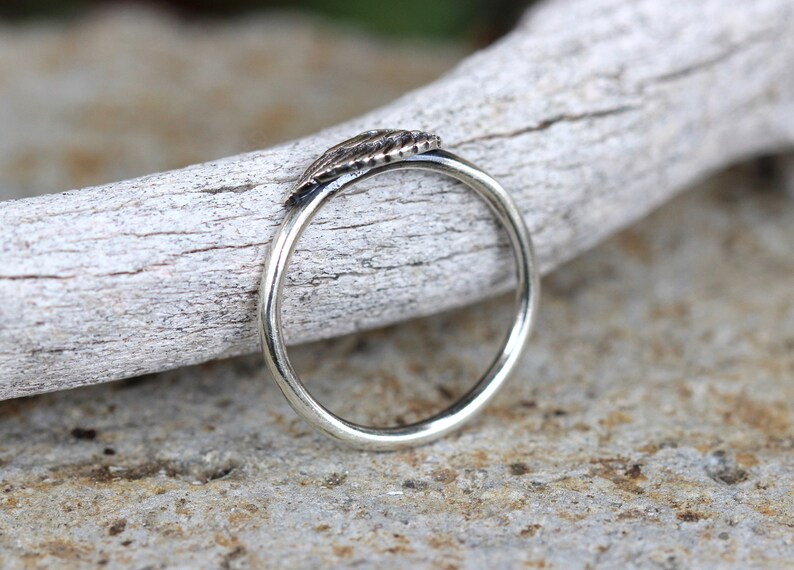 May include: A silver ring with a textured leaf design. The ring is simple and elegant.