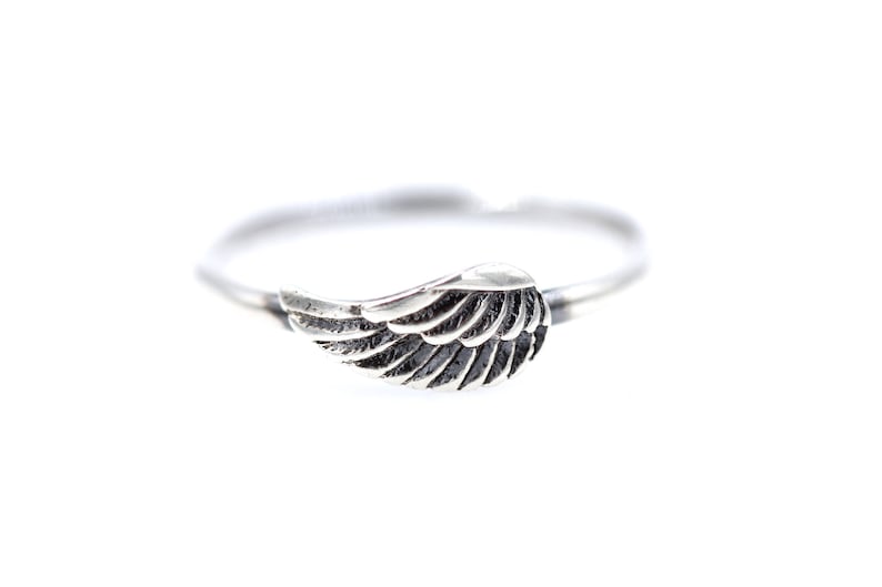 May include: A silver ring with a wing design. The wing is detailed and has a textured finish.