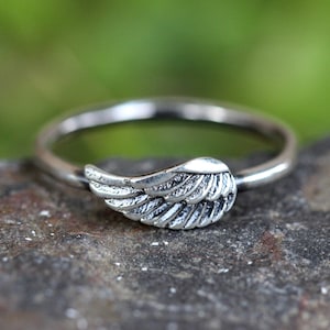 May include: A silver ring with a detailed wing design. The ring is simple and elegant.