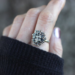 Puede incluir: Anillo de plata con un dise&ntilde;o detallado de una cara de mujer rodeada de serpientes.
