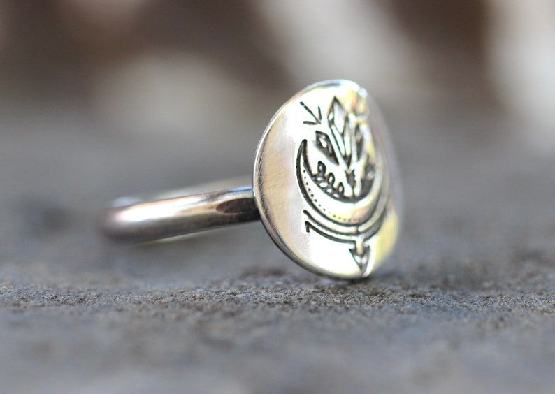 May include: A silver ring with a crescent moon and a crystal design. The ring is made of sterling silver and is a great gift for anyone who loves celestial jewelry.