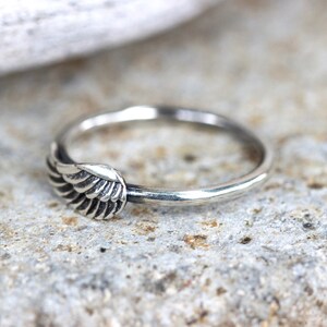May include: A silver ring with a wing design. The wing is detailed with multiple lines to create a realistic look.