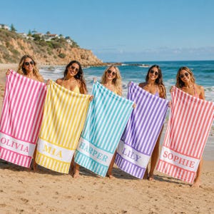 May include: Five rectangular beach towels featuring vertical stripes in pink, yellow, light blue, purple, and coral. Each towel has a solid white horizontal band at the bottom with the names Olivia, Mia, Harper, Lily, and Sophie printed in block letters.