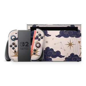 Peut inclure: Une console Nintendo Switch avec un design personnalisé. Les manettes Joy-Con et la station d'accueil de la console présentent un fond crème avec un motif céleste de nuages, d'étoiles et d'éléments botaniques. Le texte "SWITCH" est visible sur la console.