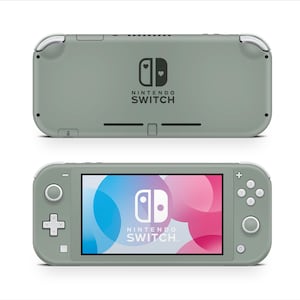 Peut inclure: Console de jeu portable Nintendo Switch Lite vert sauge. Vue de face avec écran affichant un graphisme coloré et le logo Nintendo Switch. Vue arrière avec logo et symbole cœur. Design élégant et arrondi.