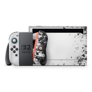 May include: A Nintendo Switch console with a white and grey body, and a black and white patterned Joy-Con controller. The console's back has a white background with black heart and splatter designs. The other Joy-Con is white and grey.