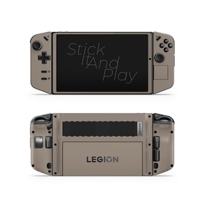 Può includere: Un dispositivo di gioco portatile Lenovo Legion color talpa, vista anteriore e posteriore. La parte anteriore presenta uno schermo nero con il testo "Stick It And Play". Il retro mostra il logo Legion.