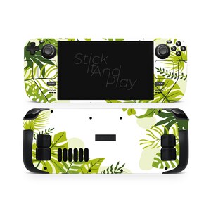 Peut inclure: Une peau de console de jeu portable avec un motif de feuilles tropicales vertes et blanches. Le texte "Stick And Play" est visible sur l'écran. La peau recouvre l'avant et l'arrière de la console.