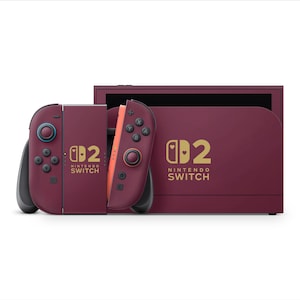 Może przedstawiać: Bordowa konsola Nintendo Switch z pasującymi kontrolerami Joy-Con. Kontrolery mają turkusowe i pomarańczowe akcenty. Konsola i kontrolery mają złote logo i napis "Nintendo Switch".