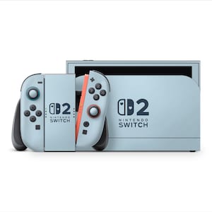 Puede incluir: Una consola Nintendo Switch azul claro con mandos a juego. Los mandos tienen botones negros y un acento rojo. La consola y los mandos presentan el texto "Nintendo Switch" y un logotipo "D2" estilizado.