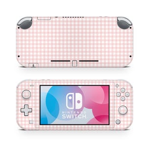 Op de afbeelding: Een Nintendo Switch Lite console en het achterpaneel, beide bedekt met een roze en wit ruitpatroon. Het scherm toont het Nintendo Switch-logo met een kleurrijke achtergrond. De console heeft een slank, afgerond ontwerp.