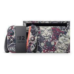 Peut inclure: Une console Nintendo Switch et ses manettes avec une peau décorative inspirée du Japon. La peau a un fond crème avec des illustrations de masques de renard, d'éventails et d'éléments floraux en rouge et bleu marine.
