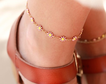 May include: A delicate gold chain anklet with small daisy charms in pink, white, and yellow.