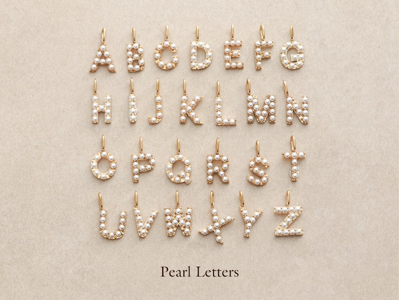 May include: A collection of gold-colored alphabet letter pendants, each encrusted with small, round pearls. The letters A through Z are displayed, each with a small loop at the top for hanging. The text "Pearl Letters" is at the bottom.