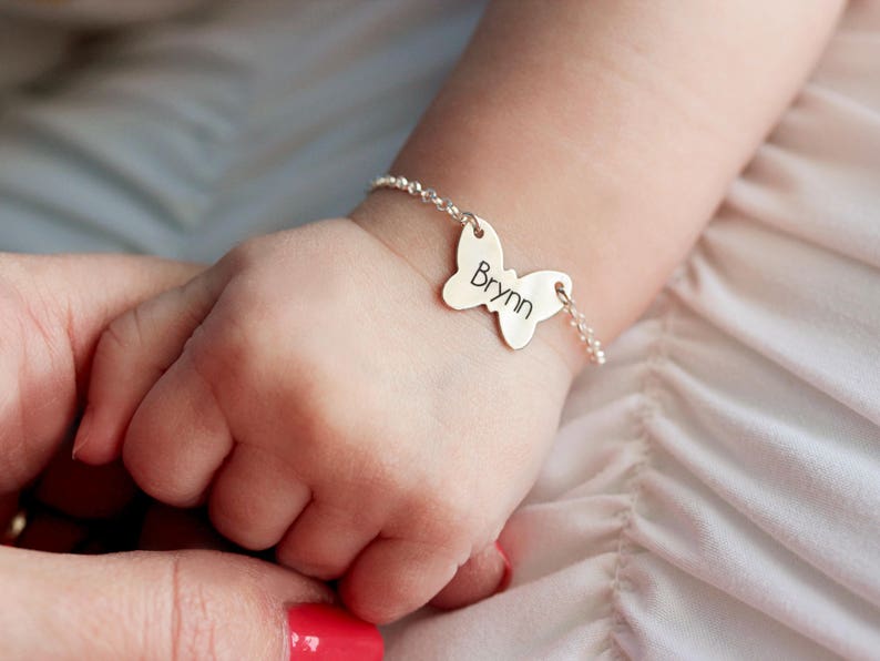 Pode incluir: Um bracelete de prata com um fecho de borboleta com o nome "Brynn" gravado.