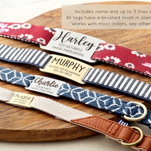 Puede incluir: Cuatro collares para perros diferentes con etiquetas de metal grabadas personalizadas. Los collares son de varios colores y patrones, incluyendo rojo con flores blancas, rayas blancas y negras, azul con un patr&oacute;n geom&eacute;trico y beige con un acento de cuero marr&oacute;n. Las etiquetas incluyen el nombre del perro, el n&uacute;mero de tel&eacute;fono y informaci&oacute;n adicional como "necesita medicamentos" o "Estoy perdido, llama a mis padres".