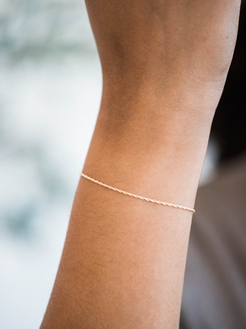 May include: A delicate gold chain bracelet with a twisted rope design.