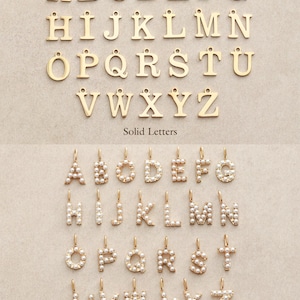 May include: A collection of gold-colored solid letter charms and pearl-studded letter charms. The upper section displays the alphabet in a simple, sans-serif font. The lower section shows the alphabet in pearl-covered letters. The text "Solid Letters" and "Pearl Letters" are below each set.