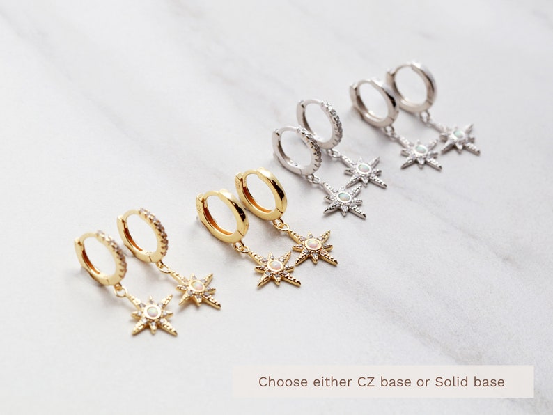 May include: A set of six gold and silver hoop earrings with a dangling star charm. Each star charm has a white opal center and is surrounded by smaller clear stones. The text "Choose either CZ base or Solid base" is visible at the bottom of the image.