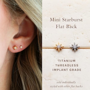 May include: Mini Starburst Flat Back titanium threadless implant grade earrings. One gold-tone and one silver-tone starburst stud, each featuring a central clear stone. Text reads: Mini Starburst Flat Back, TITANIUM THREADLESS IMPLANT GRADE.