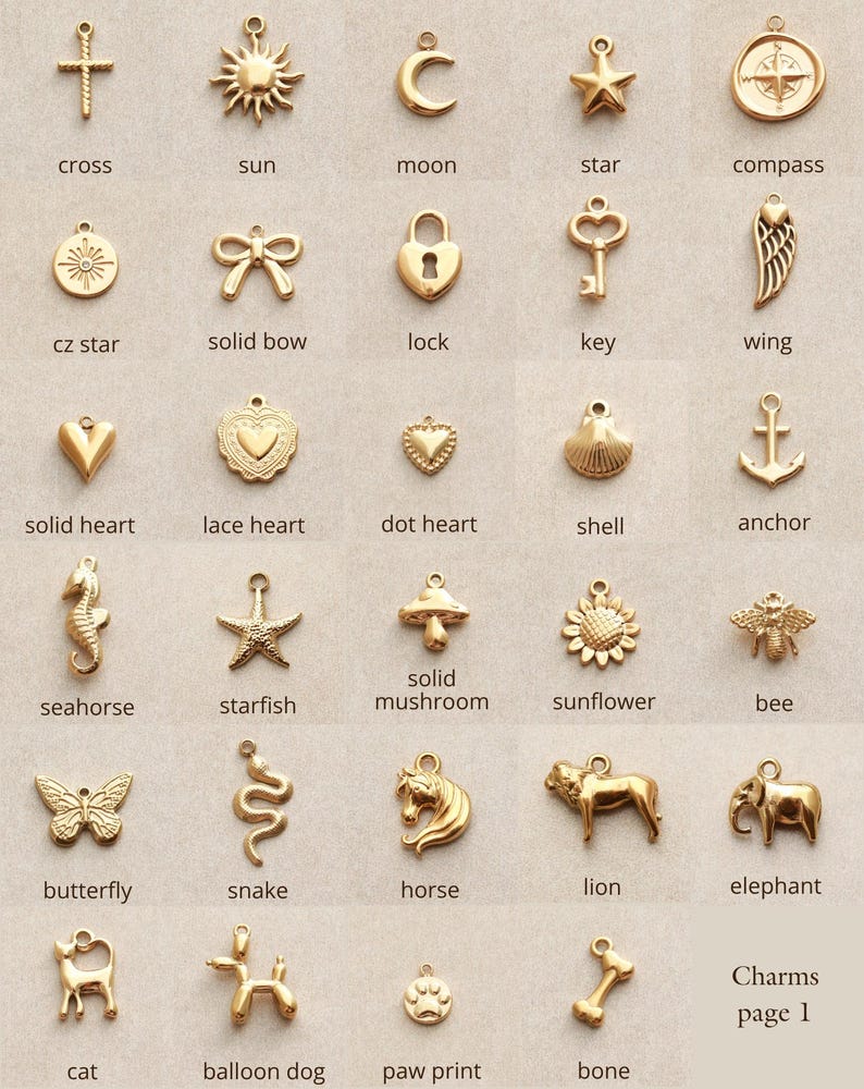 May include: A collection of gold-colored charms in various shapes, including a cross, sun, moon, star, compass, heart, key, wing, seahorse, butterfly, and more. The text "Charms page 1" is visible.