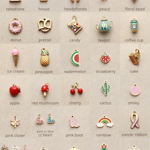 May include: A collection of gold-toned charms in various shapes, including a telephone, house, headphones, peace symbol, floral bead, donut, pretzel, candy, teapot, and coffee cup. Other charms include an ice cream cone, pineapple, watermelon, strawberry, cake, apple, red mushroom, cherry, cactus, and smiley face.