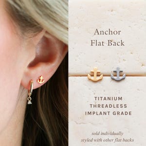 May include: Gold and silver anchor-shaped earrings. The earrings are titanium, threadless, and implant grade. The image also shows a gold hoop earring with a small charm and the text "Anchor Flat Back".