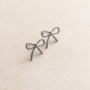May include: A pair of silver bow-shaped earrings.
