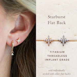 May include: Gold and silver starburst flat back earrings with clear gemstones. The earrings are titanium threadless implant grade. The image also shows a gold hoop earring with a dangling gemstone.