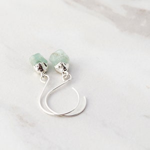 May include: A pair of silver earrings with light green gemstone drops.