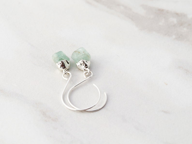 May include: A pair of silver earrings with light green gemstone drops.