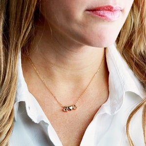 May include: A gold chain necklace with three small heart charms.