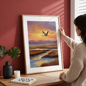 Majestic Sandhill Crane wall art for rustic decor — tranquil coastal scene capturing a dramatic sunset with soft purple clouds.