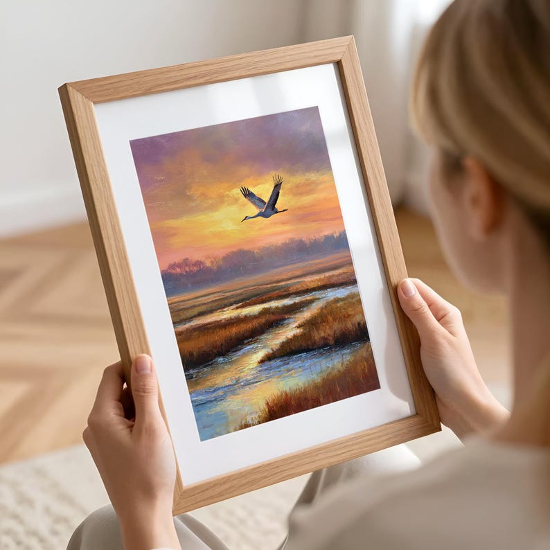 Sandhill Crane artwork for gallery wall — realistic depiction of a crane flying through a moody sunset sky with reflective water below.