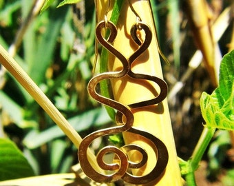 May include: Gold-toned earrings with a unique, abstract design. The earrings are made of a single, continuous piece of metal that is twisted and turned to create a series of loops and swirls.