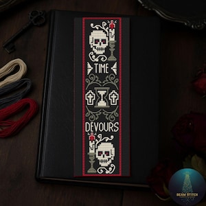 Puede incluir: Marcapáginas negro con un diseño de punto de cruz que presenta calaveras, velas y las palabras "TIME DEVOURS". El marcapáginas tiene un borde rojo y está colocado sobre un libro negro. El diseño incluye un reloj de arena y elementos florales.