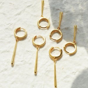 Op de afbeelding: Zes gouden oorringen met een hangende staaf. De oorringen zijn allemaal van verschillende grootte.
