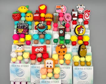 May include: A collection of colorful sewing sticks, each featuring a unique food-themed charm. Charms include a strawberry, lemon, french fries, burger, and a Kit Kat bar. The text "YOU'LL ALWAYS BE MY BEST-TEA" is visible.