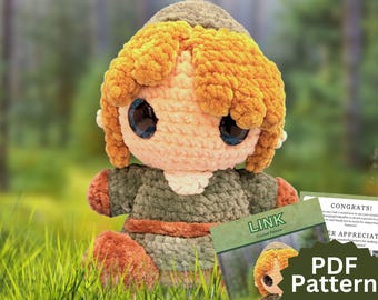 May include: A plush crochet doll featuring a large head with textured golden-yellow yarn hair, oversized dark eyes, and a peach-colored face. The doll wears a dark olive green tunic with a brown belt and matching brown boots, accompanied by a PDF pattern.