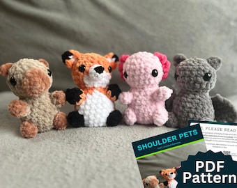 May include: Four handmade crochet shoulder pets in a row. The plush toys include a tan bear, an orange fox, a pink axolotl, and a gray bat. A PDF pattern for the toys is visible in the lower right corner.