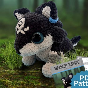 Puede incluir: Un peluche de ganchillo en blanco y negro con forma de lobo, grandes ojos oscuros, una marca blanca en la frente y un detalle azul en la oreja. Junto al peluche hay un documento titulado WOLF LINK Crochet Pattern con el texto PDF Pattern.