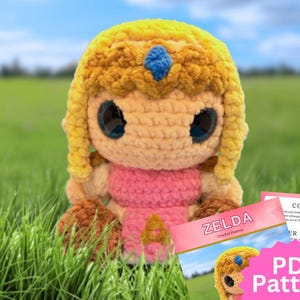 Peut inclure: Une poupée en crochet avec des cheveux jaunes ornés d'une gemme bleue, de grands yeux noirs et une tenue rose. À côté se trouve un document intitulé ZELDA Crochet Pattern avec un graphique en étoile rose portant le texte PDF Pattern.