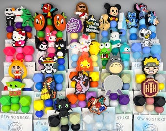 May include: A collection of colorful sewing sticks featuring various cartoon characters and designs. The assortment includes characters like Hello Kitty, Mickey Mouse, and Snoopy, with text that reads "Faith Can Move Mountains" and "Sewing Sticks".