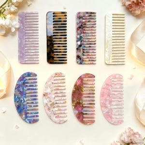 May include: A collection of eight decorative hair combs in various colors and patterns. The combs include shades of purple, tortoiseshell, marble, and pink. The combs are made of a glossy material and are arranged on a light-colored surface.