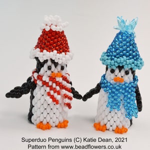 May include: Two beaded penguin ornaments, one wearing a red and white Santa hat and scarf, the other wearing a blue hat and scarf. Superduo Penguins (C) Katie Dean, 2021. Pattern from www.beadflowers.co.uk