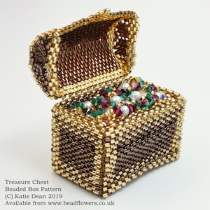 May include: A beaded treasure chest with a hinged lid open, revealing a collection of colorful beads and pearls inside. The chest is made of brown and gold beads, creating a textured and intricate design.